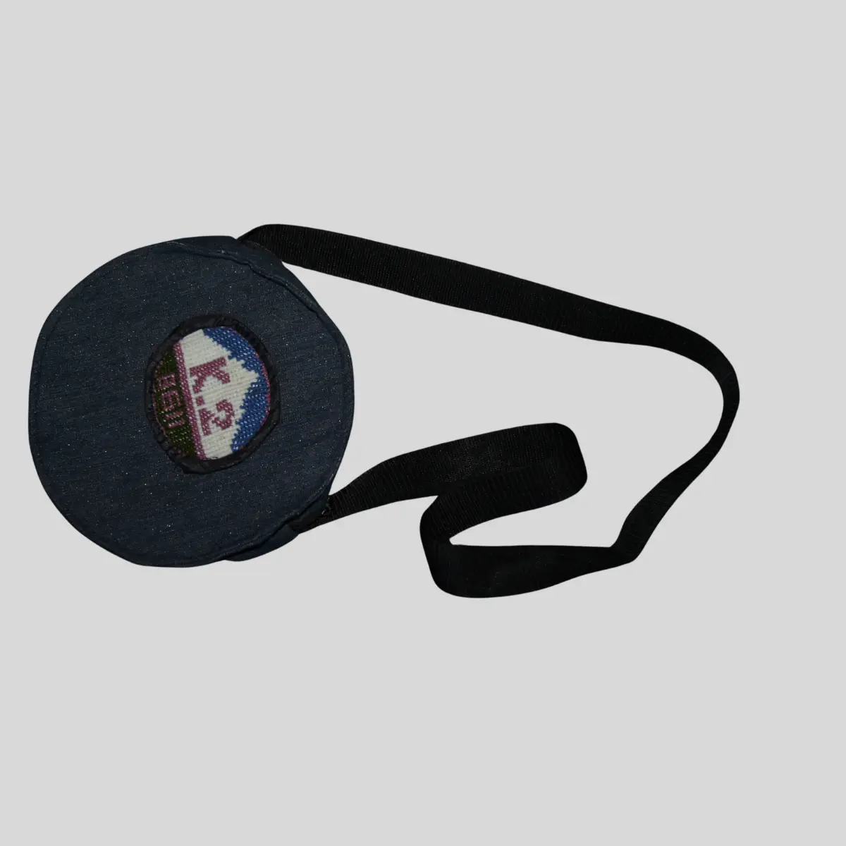 Circular burgundy shoulder bag with hand cross-stitched traditional embroidery panel and tassel detail